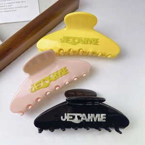 Détail de trois pinces à cheveux en acétate coloré avec inscription JE T'AIME