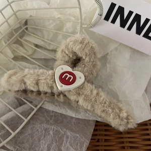 Dettaglio molletta per capelli in peluche kaki con motivo a cuore su carta bianca