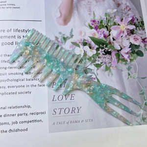 Close-up of a wide-tooth acetate hair comb with marble patterns on a magazine