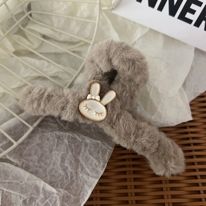 Dettaglio della pinza per capelli in peluche marrone con coniglio bianco e fiocco