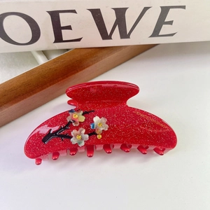 Détail de la pince à cheveux rouge en acétate avec fleurs en nacre et logo France Handmade