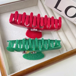 Détail de pinces à cheveux en acétate rouge et vert avec fleurs et strass élégants