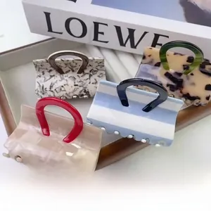 Detail of four acetate claw clips in square handle design with tortoise and marble patterns