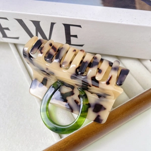 Detail view of tortoiseshell pattern hair claw clip with a green circular accent design