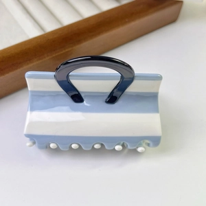 Detail showing handbag shaped hair claw clip with blue and white stripes and shiny finish