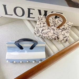 Unique handbag shaped hair claws with marble textures and blue stripes on jewelry display