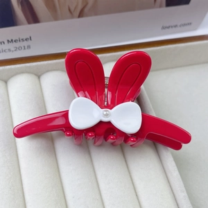 Détail de pince à cheveux oreilles de lapin rouge avec nœud blanc et fausse perle