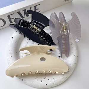 Three large acetate hair claws in black, mauve and cream with elegant shell-inspired designs