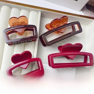 Detail view of heart-shaped acetate claw clips in amber and red inside a jewelry box