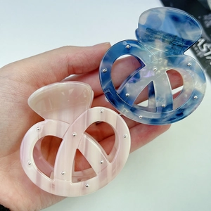 Dettaglio molletta per capelli marmorizzata con borchie argento e design a spirale