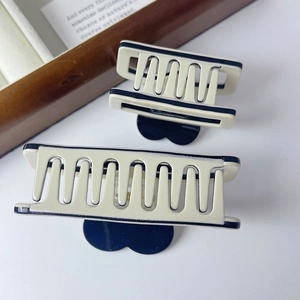 Detailed view of cream and navy blue acetate shark hair clips in two sizes on white surface
