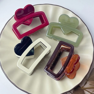 Detail of heart-shaped hair claws in multiple colors arranged on a ceramic tray