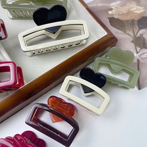 Macro detail of colorful acetate heart hair claws on a decorative wooden tray
