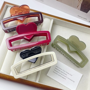 Detail view of five assorted heart hair claws in amber, red, black, beige and green