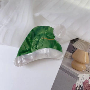 Gros plan détaillé d'une pince à cheveux en acétate vert au motif de chapeau de Noël