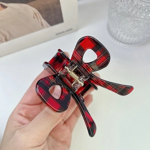 Close-up of a red and black plaid bow hair claw clip with a premium golden spring