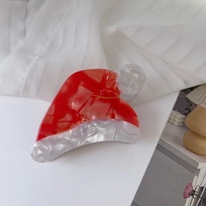 Détail macro de la pince à cheveux en acétate rouge et blanc au motif de bonnet de Noël