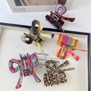 Close-up of five acetate butterfly hair claws in various vibrant patterns on a white tray