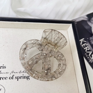 Pinza per capelli in acetato grigio marmorizzato con punti metallici e design a nodo