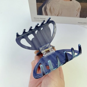 Vue détaillée de la pince à cheveux en acétate marbré bleu foncé avec ressort doré
