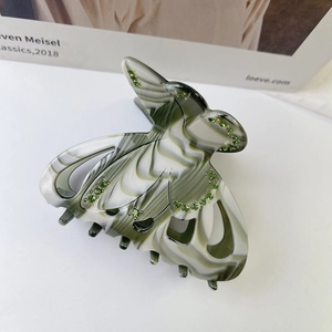 Gros plan sur la pince à cheveux papillon en résine marbrée et strass verts