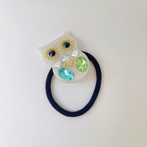 Dettaglio dell'elastico per capelli a civetta in acetato con strass colorati e fascia blu