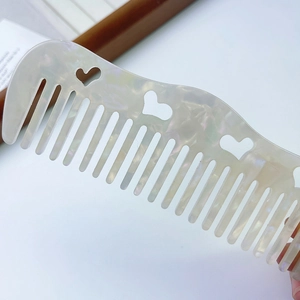 Elegant wave-shaped acetate hair comb with hollow heart patterns and pearlescent finish