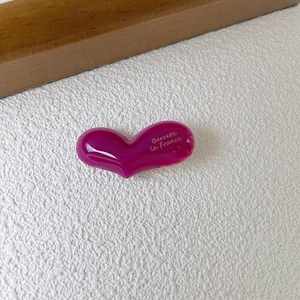 Detailed macro view of 4mm thick pink acetate heart hair clip with gold lettering