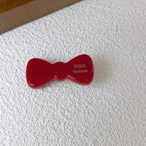 Dettaglio del fermaglio per capelli a fiocco rosso con scritta dorata France Handmade