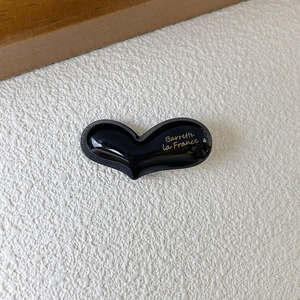 Close-up of black acetate heart hair clip with gold Barrette La France lettering