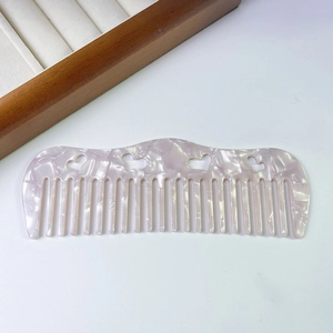 Detail of marble texture acetate hair comb with hollowed heart patterns and smooth teeth