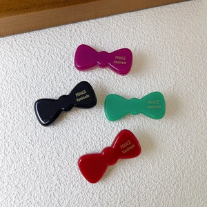Fermagli per capelli a fiocco in acetato viola, nero, verde e rosso con scritte