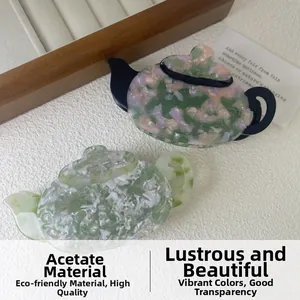 Detailed close-up of acetate teapot hair clips with floral patterns on a velvet background