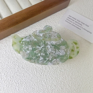 Detail of jade-like acetate hair claw clip with teapot design and marble texture