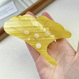 Vue détaillée d'une pince à cheveux feuille de ginkgo jaune avec nervures dorées et perles
