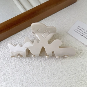 Dettaglio di una molletta per capelli LOVE beige con rilievo a cuore su superficie strutturata