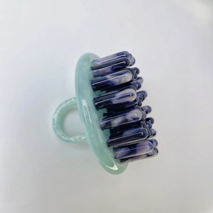 Detail showing marble texture massage teeth and ring handle of acetate scalp comb