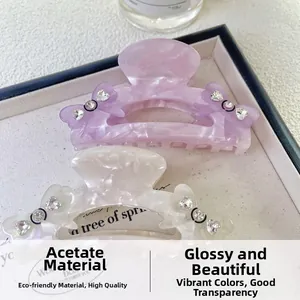 Détail de pinces à cheveux en acétate marbré avec nœud en strass en blanc et violet