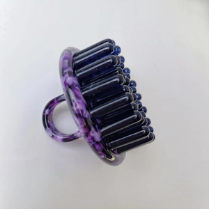 Close-up of the ergonomic purple marble handle and blue silicone scalp massage bristles