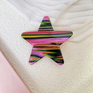 Detalle de pinzas para el pelo de estrella con rayas de colores sobre fondo blanco texturizado