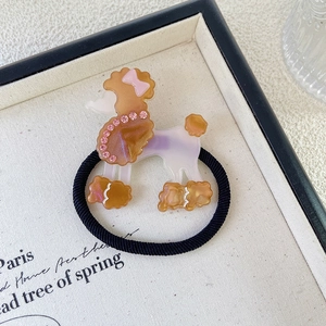 Detalle de goma de pelo de caniche con pedrería rosa y una banda elástica negra suave