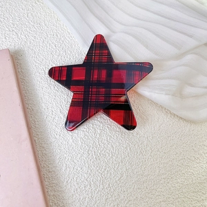 Detalle de una pinza para el cabello de estrella a cuadros rojos y negros sobre blanco