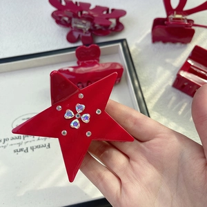 Detailed close-up of a festive red star-shaped hair claw clip with sparkling rhinestones