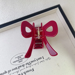 Elegant red bow-shaped acetate hair claw clip with glossy finish and gold metal spring