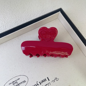 Detailed macro view of a glossy dark red acetate hair claw with embossed heart design