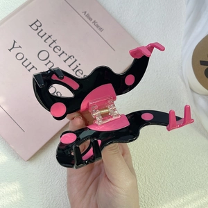 Détail de la pince à cheveux papillon à pois roses avec ressort en métal doré robuste