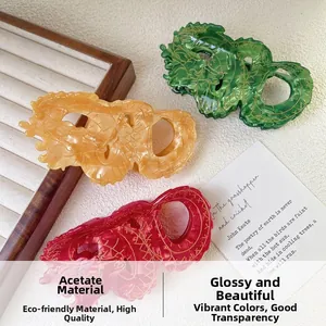 Detailed shot of emerald, amber, and burgundy dragon-shaped acetate hair claws