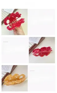 Detail view of large dragon-shaped hair claw clips in red and amber acetate texture