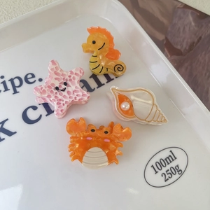 Detail of sea creature hair clips featuring shell, crab, and seahorse with pearl accents