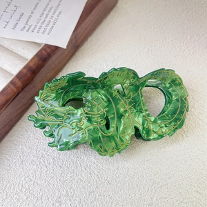Detail shot of green marble-patterned dragon hair claw clip with golden scale outlines